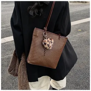 Detail of dark brown woven tote bag featuring a leopard print heart plush charm