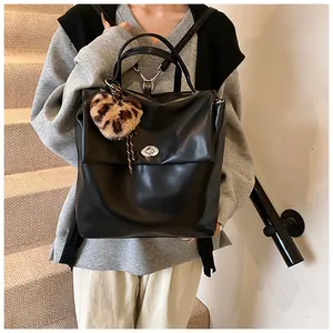 Detail eines schwarzen Kunstleder-Rucksacks mit Drehverschluss und Leoparden-Herzanhänger