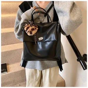 Detail eines schwarzen minimalistischen Lederrucksacks mit silbernem Drehverschluss und Herzanhänger
