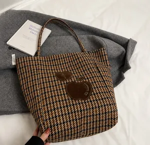 Detail van de winterse tote bag met houndstooth-patroon en bruine applicatie van een appel