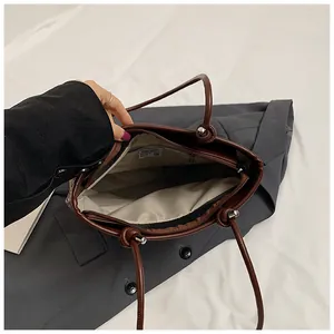 Interior view of brown woven tote bag featuring beige lining and a metal zipper pocket