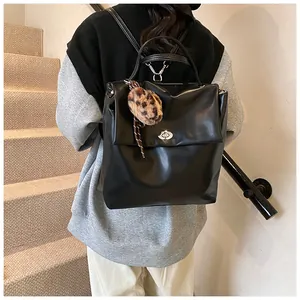 Detail eines schwarzen Kunstlederrucksacks mit Metalldrehverschluss und Leoparden-Bommel