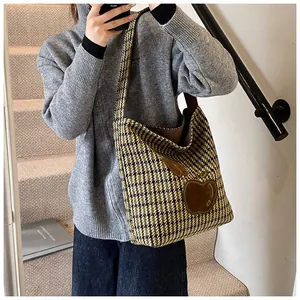 Detail van de houndstooth draagtas met appelpatch getoond op de schouder in een scène