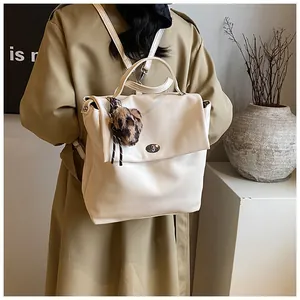 Detail eines cremeweißen PU-Lederrucksacks mit Leopardenherz-Anhänger und Metalldrehverschluss