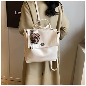 Rückansicht eines beigen PU-Lederrucksacks mit Herzanhänger an einem Modell im Trenchcoat