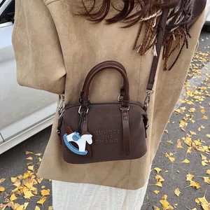 Borsa bowling in pelle marrone con ciondolo a cavallo blu in una scena autunnale