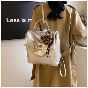 Nahaufnahme silberner Rucksack mit Leoparden-Herzanhänger auf einem Trenchcoat