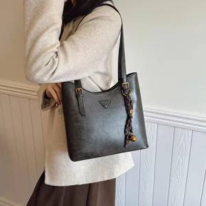Sac cabas en cuir vintage gris foncé avec plaque triangulaire porté à l'épaule pour femme