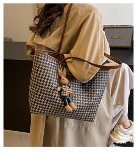 Classic houndstooth tote bag shown on model with cute rabbit pendant and brown leather straps