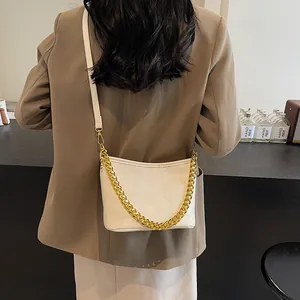 Weiße gesteppte Hobo-Tasche mit Goldkette, am Modell in einem Café präsentiert