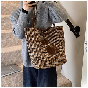 Klassieke houndstooth draagtas met leren handvatten en appel-applicatie gedragen door model