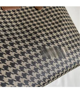 Detail of houndstooth fabric texture and brown leather handle on a stylish tote bag