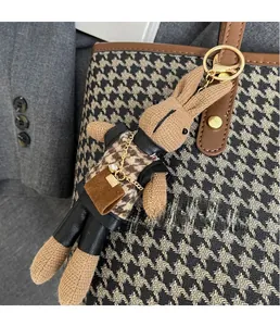 Detail of creative plush rabbit bag charm with houndstooth vest and gold keychain
