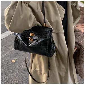 Borsa tote nera con trama a coccodrillo e chiusura a girello dorata vista in strada