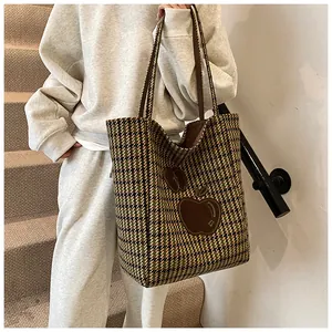 Detail van grote houndstooth draagtas met decoratieve appel-patches en schouderbanden