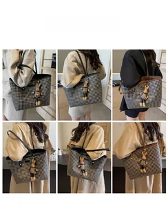 Detail view of houndstooth tote bag with plush bunny charm and various leather strap options