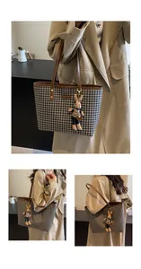 Detail of houndstooth tote bag with brown leather handles and a cute bunny pendant