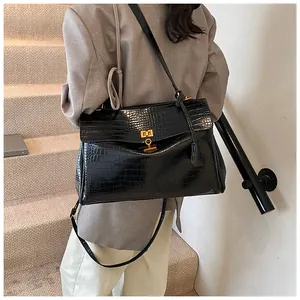 Dettaglio borsa shopper nera in coccodrillo con chiusura girevole dorata sulle scale