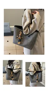 Detail view of large houndstooth tote bag with a cute plush bunny charm and leather trim