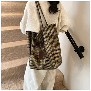 Detail van de pied-de-poule shopper met geborduurde appelpatches en wollen textuur