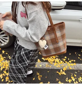 Gros plan du sac cabas à carreaux marron avec anses en cuir et charm en forme de cœur
