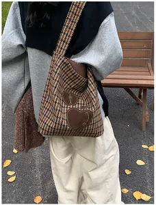 Houndstooth draagtas met appelborduurwerk getoond in een herfstige buitenomgeving