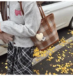 Détail du sac cabas à carreaux marron avec anses en cuir et breloque coeur en peluche