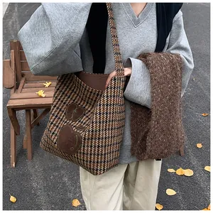 Detail van houndstooth crossbodytas met appelpatches en pluchen bruine sjaalstyling