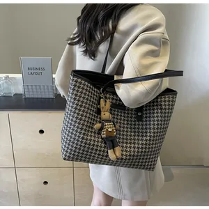 Detail of houndstooth tote bag with leather straps and a cute plush rabbit pendant