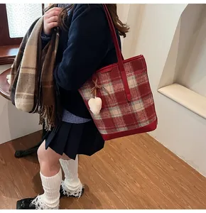 Détail du sac cabas à carreaux rouges avec garniture en cuir et breloque coeur
