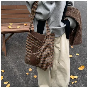 Detail van de houndstooth draagtas met lederen appel-patches in een herfstachtige setting