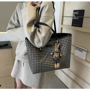 Detail of houndstooth tote bag with a matching rabbit charm and black leather straps