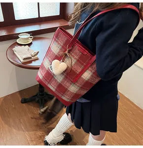 Détail du cabas à carreaux rouges avec nœud en cuir et breloque cœur en peluche