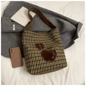 Detail van de pied-de-poule tas met groene appel patches en tweed textuur