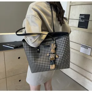 Detail of houndstooth tote bag with a matching plush bunny charm on a wooden shelf