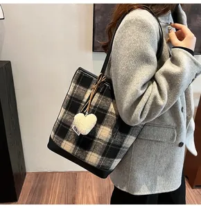 Détail du cabas à carreaux avec pendentif cœur et texture en laine porté par un mannequin