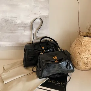 Borsa nera con motivo a coccodrillo e chiusura dorata in un ambiente di lusso