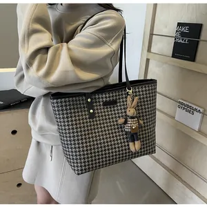 Detail of houndstooth tote bag featuring a cute bunny charm and gold hardware accents