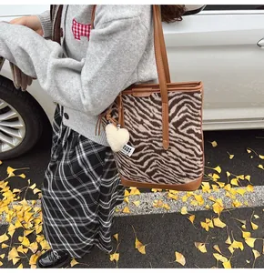Détails du sac cabas peluche à motif zèbre avec anses en cuir et breloque coeur