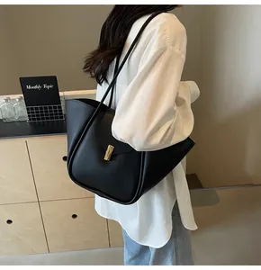 Détail d'un sac cabas en cuir noir minimaliste avec une boucle métallique dorée