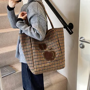 Retro houndstooth draagtas met bruine appel-patches getoond als een schoudertas op model