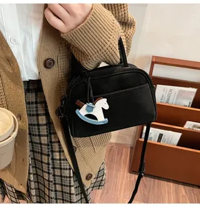 Detail of black mini square bag with cute rocking horse charm on a retro outfit