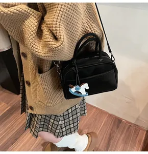 Detail view of a black fashion crossbody bag with a decorative rocking horse charm on a model