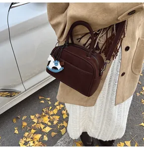 Detail of dark brown square boston bag with adjustable strap and blue horse charm