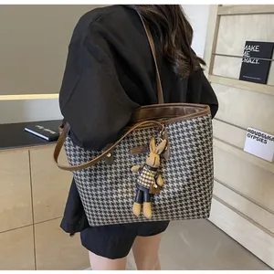 Detail of houndstooth tote bag featuring leather straps and a cute rabbit doll charm