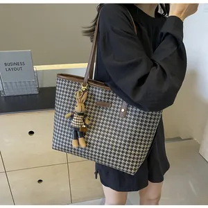 Detail of houndstooth tote bag with brown leather handles and cute rabbit charm