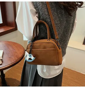 Detail of caramel leather crossbody bag with horse charm on a wooden background