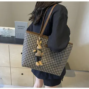 Detail of houndstooth tote bag featuring dark brown leather trim and a cute rabbit charm