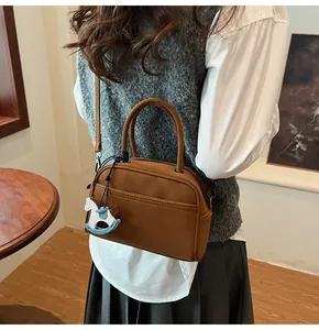 Brown leather Boston square bag with stylish horse charm shown on model in warm setting