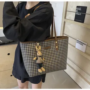Detail of houndstooth tote bag with brown leather straps and cute knit rabbit charm